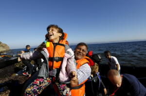 A Syrian refugee girl is lifted by her father soon after arriving on a dinghy at a beach on the Greek island of Lesbos after crossing a part of the Aegean Sea from Turkey September 18, 2015. REUTERS/Yannis Behrakis