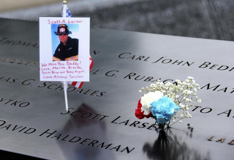 A photograph and message for fallen New York City Firefighter Scott A Larson along with flowers are seen left on his inscribed name at the edge of the north pool during memorial observances held at the site of the World Trade Center in New York, September 11, 2014. REUTERS/Chang Lee/Pool