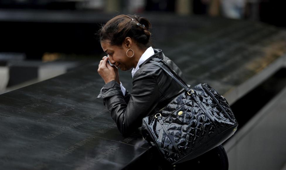 A woman who did not wish to be identified pauses at the edge of the North Pool during memorial observances on the 13th anniversary of the 911 attacks at the site of the World Trade Center in New York, September 11, 2014. REUTERS/Justin Lane/POOL