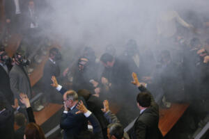 epa05170046 Lawmakers of the ruling parties vote (front) as opposition lawmakers throw tear gas during a plenary session at Kosovo's parliament in Pristina, Kosovo, 19 February 2016. Kosovo's opposition political parties protest demanding the resignation of Kosovo's government after agreements that has been reached in Brussels, during the EU-brokered dialogue between Kosovo and Serbia. EPA/VALDRIN XHEMAJ