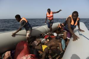 TOPSHOT - EDITORS NOTE: Graphic content / Migrants step over dead bodies while being rescued by members of Proactiva Open Arms NGO in the Mediterranean Sea, some 12 nautical miles north of Libya, on October 4, 2016. At least 1,800 migrants were rescued off the Libyan coast, the Italian coastguard announced, adding that similar operations were underway around 15 other overloaded vessels. / AFP / ARIS MESSINIS (Photo credit should read ARIS MESSINIS/AFP/Getty Images)