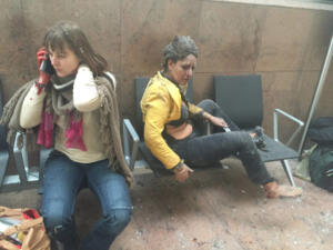 BRUSSELS, BELGIUM - MARCH 22: (EDITOR'S NOTE: Original raw image shot on a mobile phone) Flight attendant Nidhi Chaphekar (R) reacts in the moments following a suicide bombing at Brussels Zaventem airport on March 22, 2016 in Brussels, Belgium. Georgian journalist Ketevan Kardava, special correspondent for the Georgian Public Broadcaster, was travelling to Geneva when the attack took place, she was knocked to the floor and began to take photographs in the moments that followed. At least 31 people were killed and more than 260 injured in a twin suicide blast at Zaventem Airport and a further bomb attack at Maelbeek Metro Station. Two brothers are thought to have carried out the attacks and a manhunt is underway for a third suspect. (Photo by Ketevan Kardava/Getty Images)